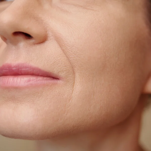 Une femme avec quelques rides sur le visage, affichant une expression douce et sereine.