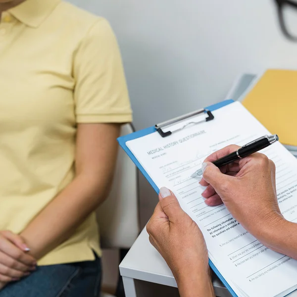 Une femme assise sur une chaise tenant un clipboard, regardant attentivement ses notes.