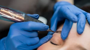 Femme recevant un maquillage permanent des sourcils à l'aide d'une machine dans un salon de beauté.