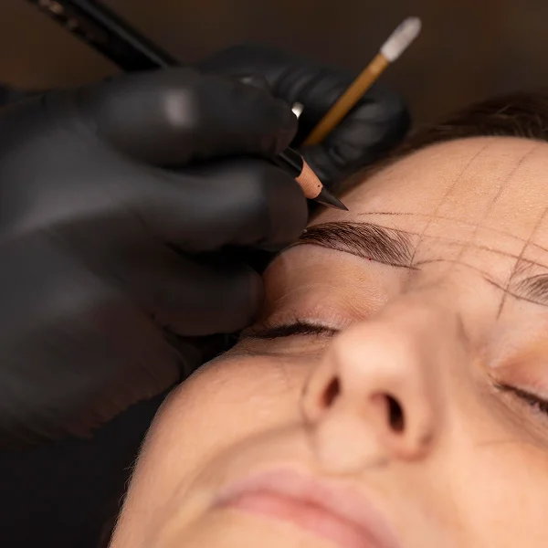 Une femme se fait faire des sourcils par micropigmentation dans un salon de beauté.